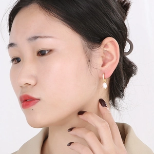 Gros plan de boucles d'oreilles créoles en or 18 carats avec perle d'eau douce sur modèle