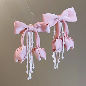 Detail of pink fabric bow hair accessories with flower buds and white beaded tassels