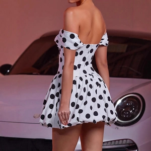Dettaglio mini abito bianco a pois con schiena scoperta su sfondo di auto di lusso