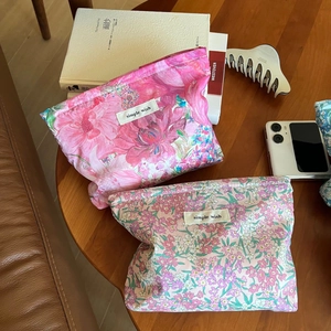 Close-up of floral liberty print cotton makeup bags with simple wish label on a wooden table