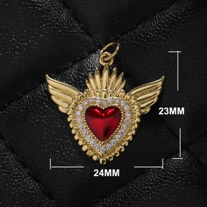 Detail view of a 23mm x 24mm gold heart pendant with red stone and wings on black leather