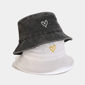 Washed cotton bucket hats in black and white with heart embroidery on a grey background