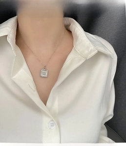 Detailed view of silver butterfly rectangle pendant on a beaded chain worn by a model