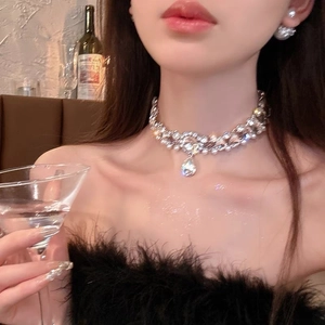Close-up of sparkling rhinestone bow necklace with pearl pendant on a model neck