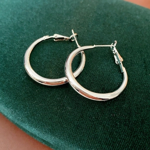 Close-up of elegant silver hoop earrings on a luxury dark green velvet surface