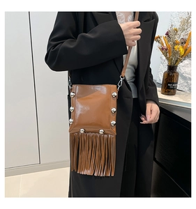Close-up of brown fringe crossbody bag with silver studs on a stylish female model