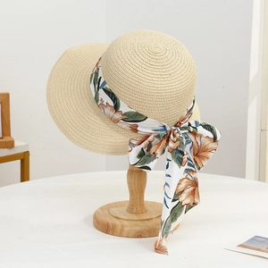 Close-up of beige straw sun hat featuring a large orange floral print ribbon bow