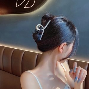 Detailed view of a large gold metal hair claw clip with elegant pearls on a woman's hair