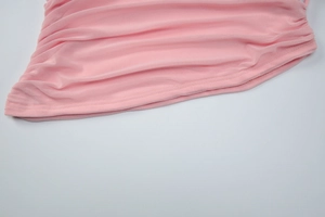 Detail of pink knitted top showing elastic ruched texture and fine pleated fabric design