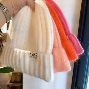 Close-up of colorful thick knit beanies showing ribbed texture and fabric labels