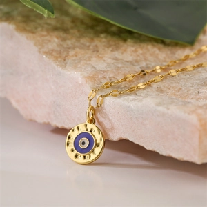 Macro shot of gold Evil Eye enamel pendant on flat link chain with natural stone
