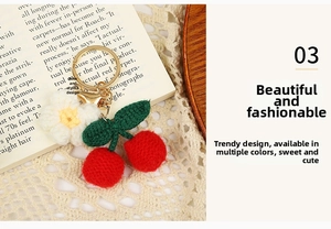Detail view of handmade crochet cherry charm with green leaves and a small white flower