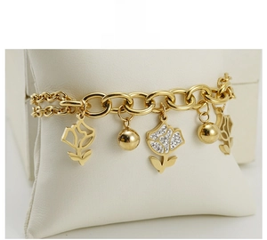 Detail of gold chain bracelet with polished rose charms and white zircon stone inlay
