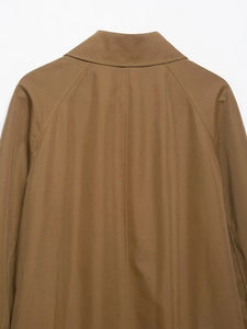Detailed view of tan trench coat showing twill cotton texture and shoulder stitching