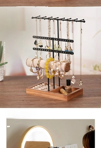 Detail view of multi-layer jewelry stand with necklace hooks and wooden ring tray base