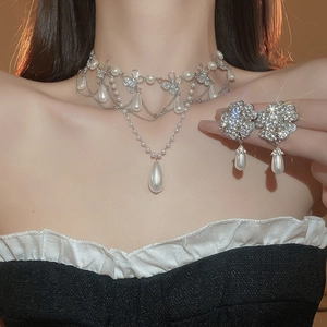 Close-up of floral diamond necklace and matching pearl earrings on a model's neck
