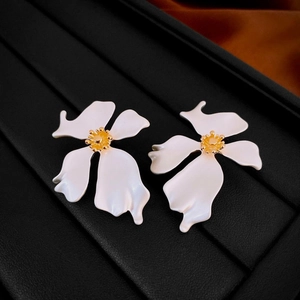 Close-up of white flower earrings with gold stamens on a black jewelry tray