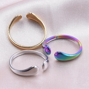 Minimalist open rings in gold, silver, and iridescent finishes on soft pink silk fabric