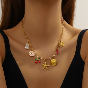 Gold multi-charm necklace featuring starfish, cherry and heart pendants worn by a model