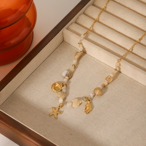 Golden starfish and seashell beaded necklace on beige jewelry tray with ocean vibes