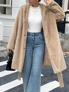 Détail d'un élégant manteau long en fausse fourrure beige avec boutons pression et ceinture