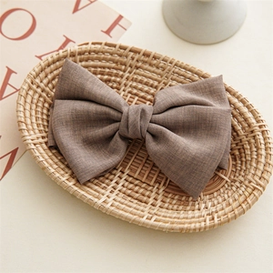 Detailed view of chocolate brown twill fabric texture on a knotted bow hair clip