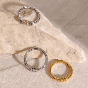 Macro shot of gold and silver minimalist steel rings with three movable beads on stone