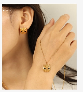 Close-up of elegant gold owl pendant necklace and earrings set with black crystals
