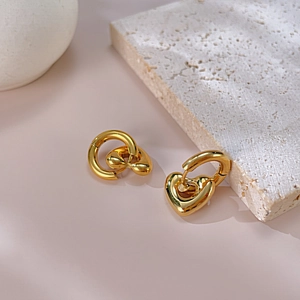 Détail de boucles d'oreilles cœur dorées élégantes sur des accessoires de pierre