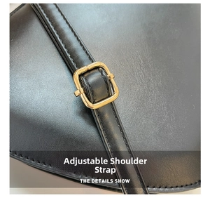 Close-up of matte black leather bag with golden adjustable strap buckle and fine stitching