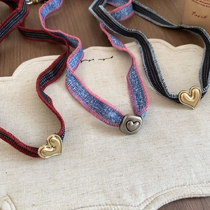 Detailed close-up of heart charms on denim and striped fabric chokers with metal accents