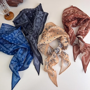 Flat lay of four paisley printed fabric scarves in blue, black, beige, and caramel tones