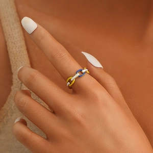 Close-up of adjustable enamel chain ring in yellow, white and blue on a model's finger