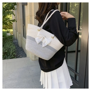 Detail of hand-woven tote bag with grey accents, white bow and stylish knotted shoulder strap