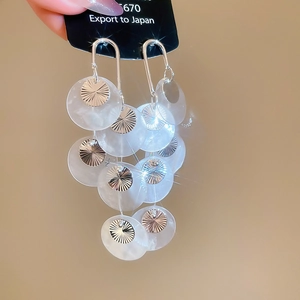 Detail view of multi-layered round pearl tassel earrings held by hand for style