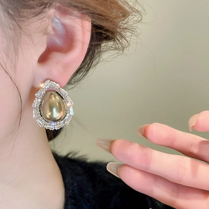 Détail des boucles d'oreilles goutte d'eau avec cadre doré et zircons étincelants