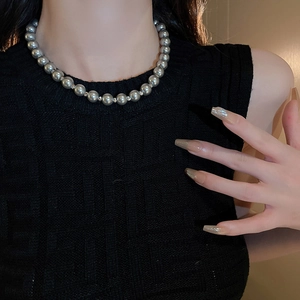 Vintage geometric pearl choker necklace displayed on a model wearing black knitwear