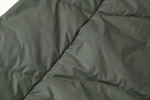 Detail of dark olive green quilted fabric with fine stitching for winter jackets