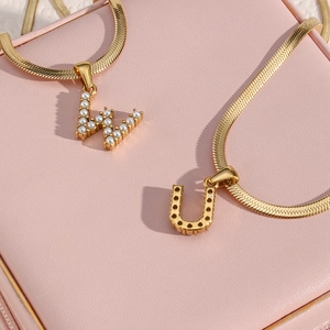 Detail of 18K gold-plated flat herringbone chain with pearl-inlaid W and U letter pendants