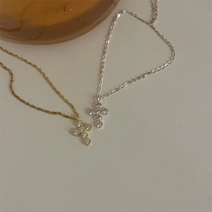 Close-up of gold and silver cross necklaces featuring shimmering round zircon stones