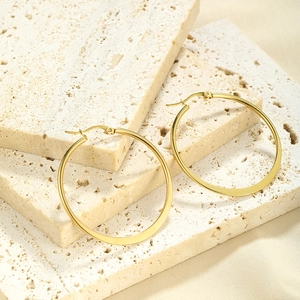 Close-up of golden round hoop earrings on a minimalist natural stone background