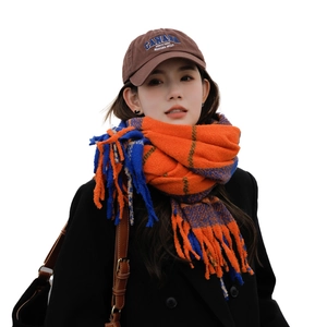 Model wearing orange and blue plaid tassel scarf with a brown Canada baseball cap