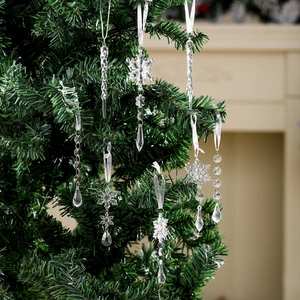 Macro detail of transparent acrylic Christmas snowflake and icicle ornaments on tree
