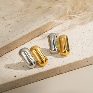 Macro shot of two-tone capsule earrings in gold and silver on stone display