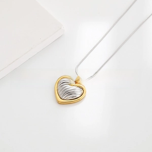 Detail of two-tone heart pendant with ribbed texture on a minimalist metal snake chain