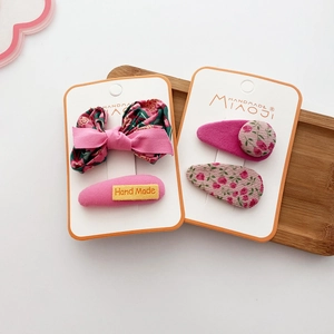 Detail of handmade floral bow hair clips and oval fabric barrettes on display card
