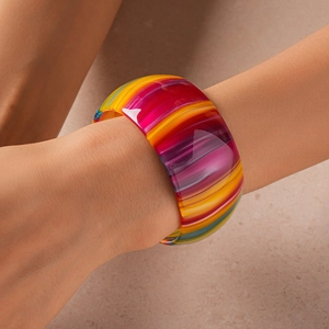 Gros plan d'un large bracelet en acétate aux rayures colorées et finition polie