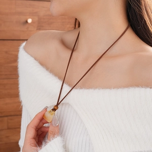 Detail of stone pendant necklace with brown wood beads and gold metal accents on model