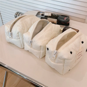 Détail de trousses de maquillage matelassées blanches avec étiquette brodée française
