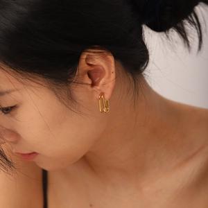 Close-up of golden double-layer geometric earrings worn by a model in luxury style